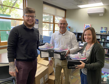 3 adults, each holding a pair of shoes